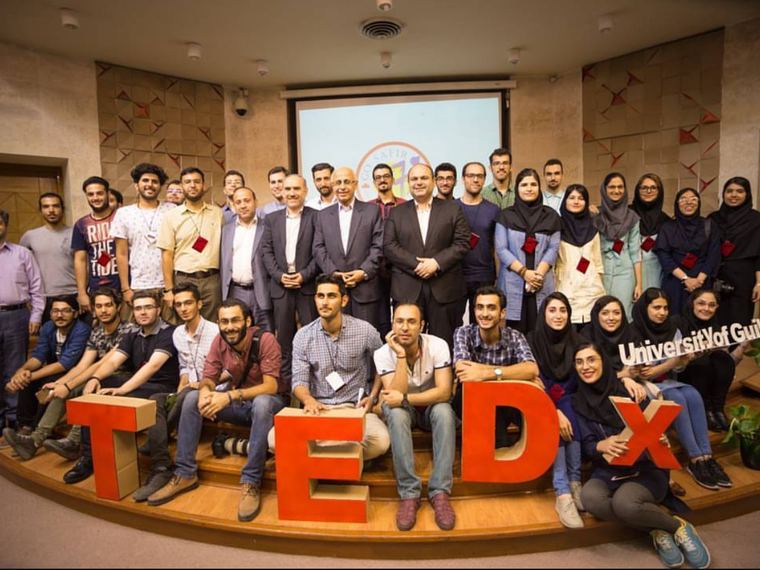 Speakers and volunteers grouped behind large red TEDX letters at TEDx University of Guilan